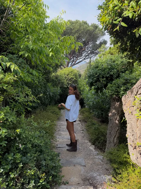 Vinaya walking down a garden path between pines in the South of France