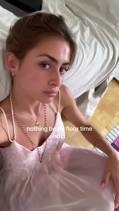 Vinaya lying on the floor in a pink slip dress, caption nothing beats floor time